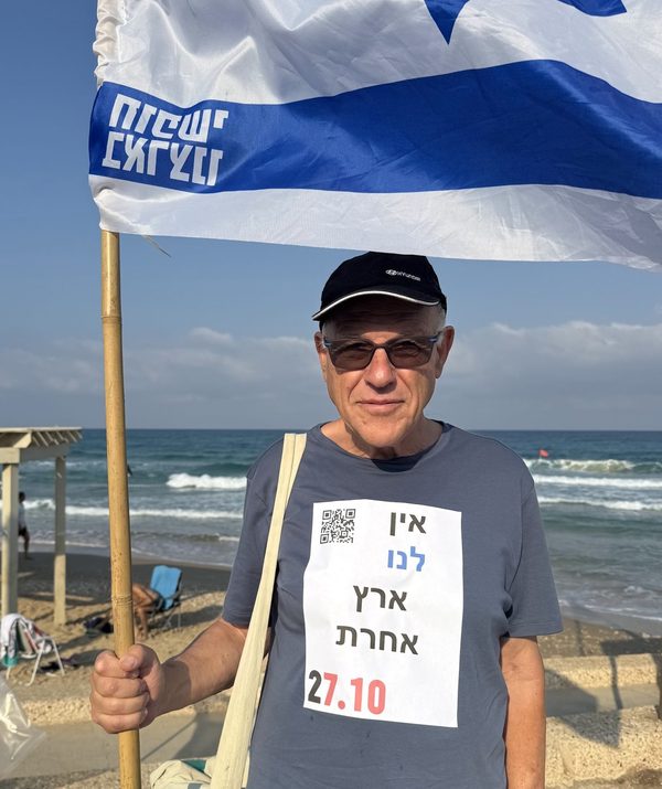 מפגין עם דגל ישראל בחוף הים, על חולצתו מדבקת אין לנו ארץ אחרת 27.10
