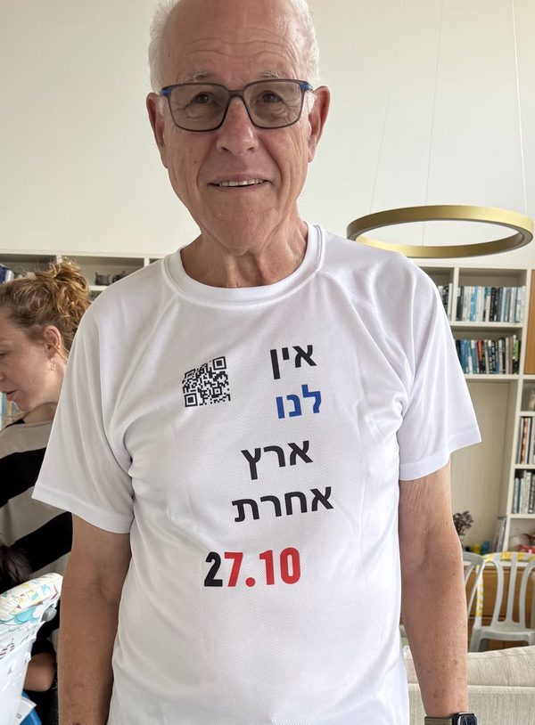 גבר לובש חולצה לבנה עם הכיתוב אין לנו ארץ אחרת 27.10